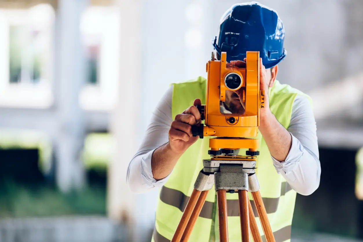 Surveyor using equipment on construction site.